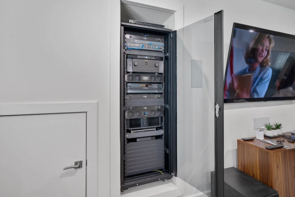 A custom AV theater system built into a wall with the door open